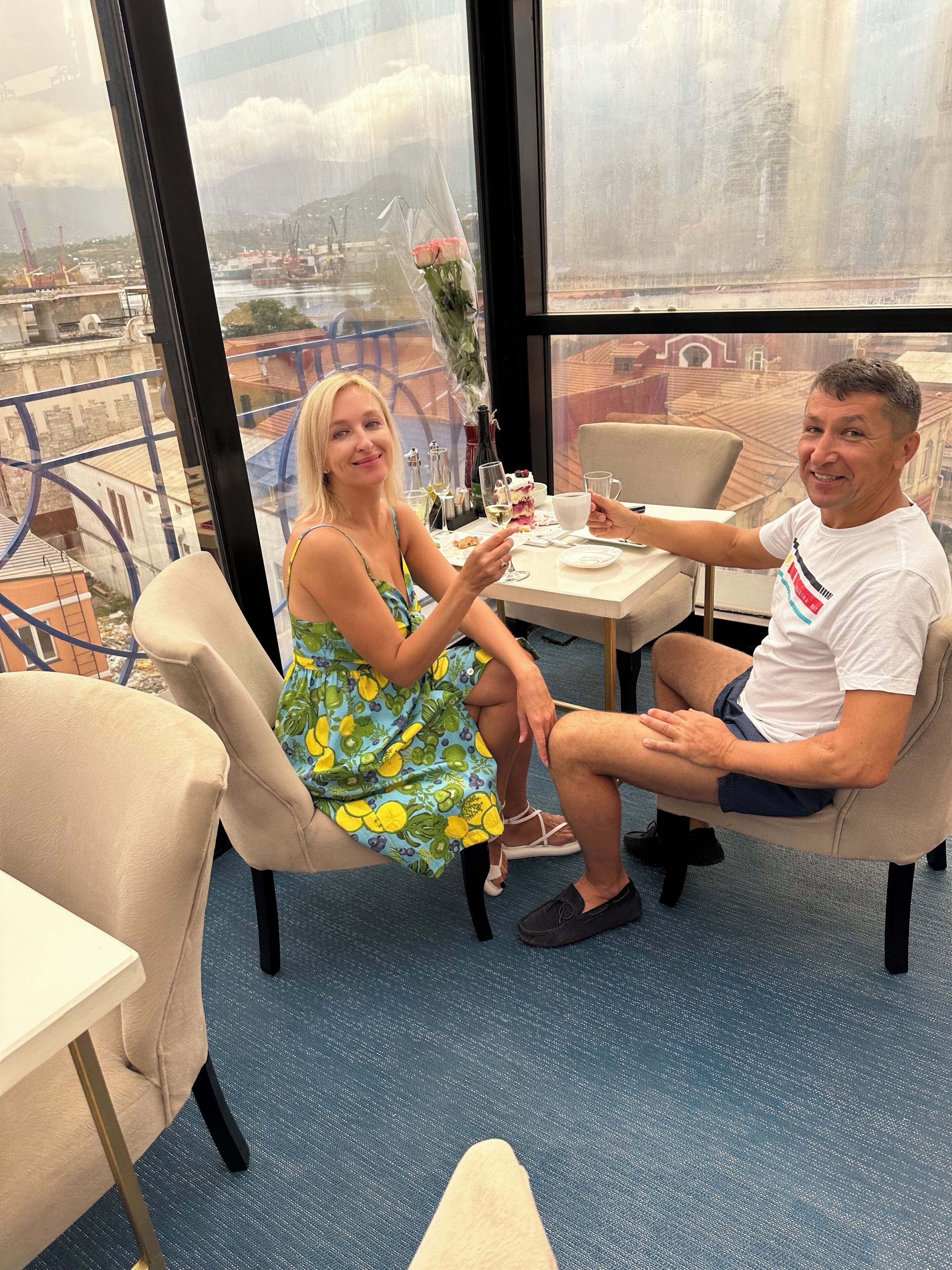 Un coin repas avec une table dressée pour deux personnes, une vue sur la ville à travers de grandes fenêtres et un balcon doté d’une balustrade.