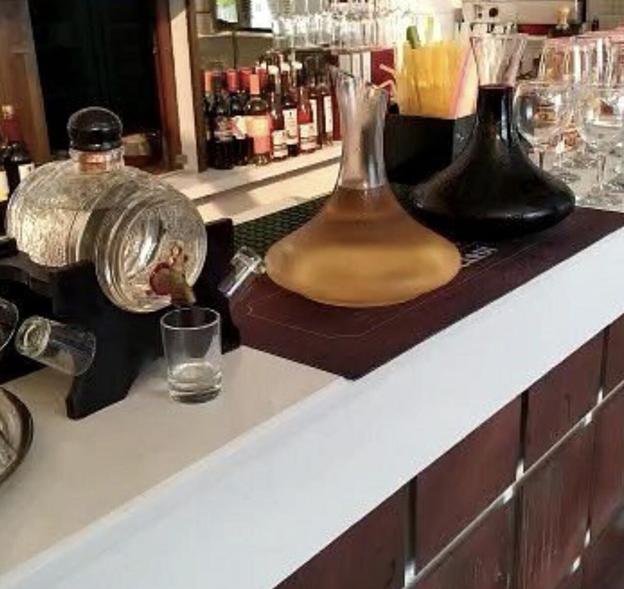 Un coin bar avec une grande carafe, une bouteille de spiritueux et un verre.