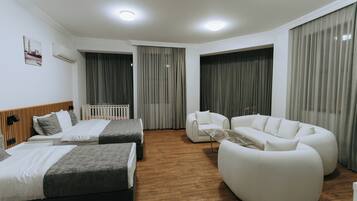 A modern hotel room with two beds, a white sofa, and a white armchair.