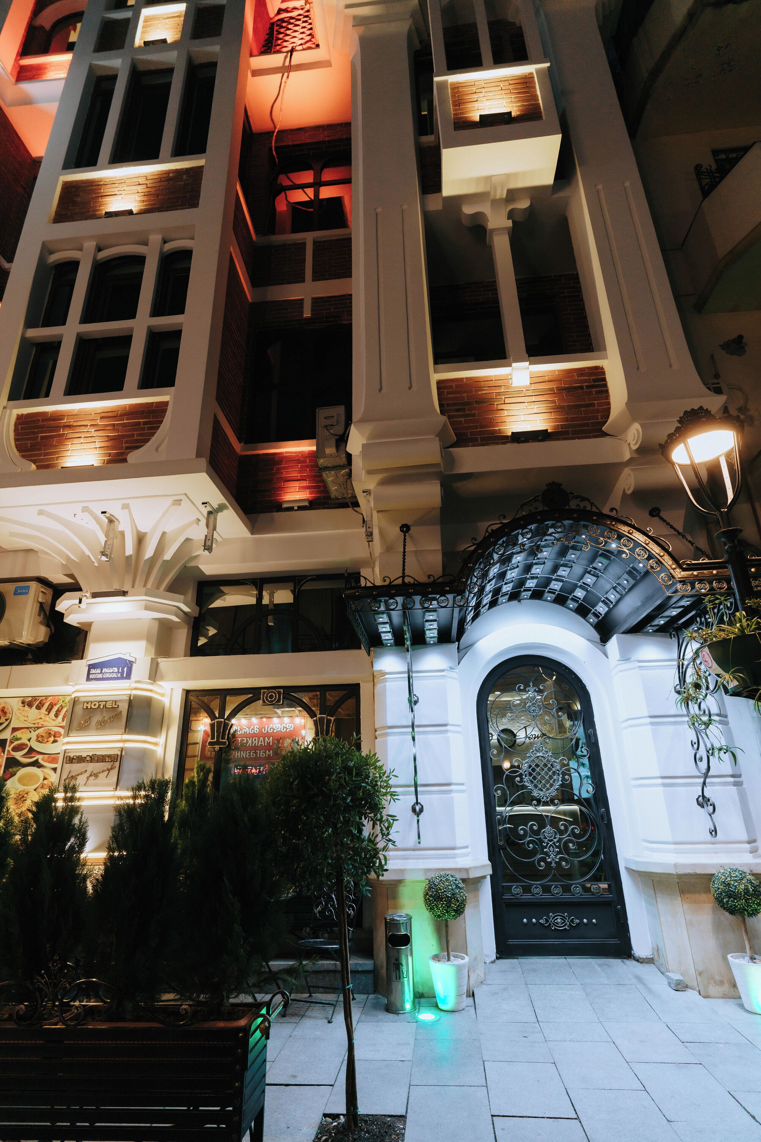 A hotel entrance with a grand archway, multiple balconies, and a well-lit facade.