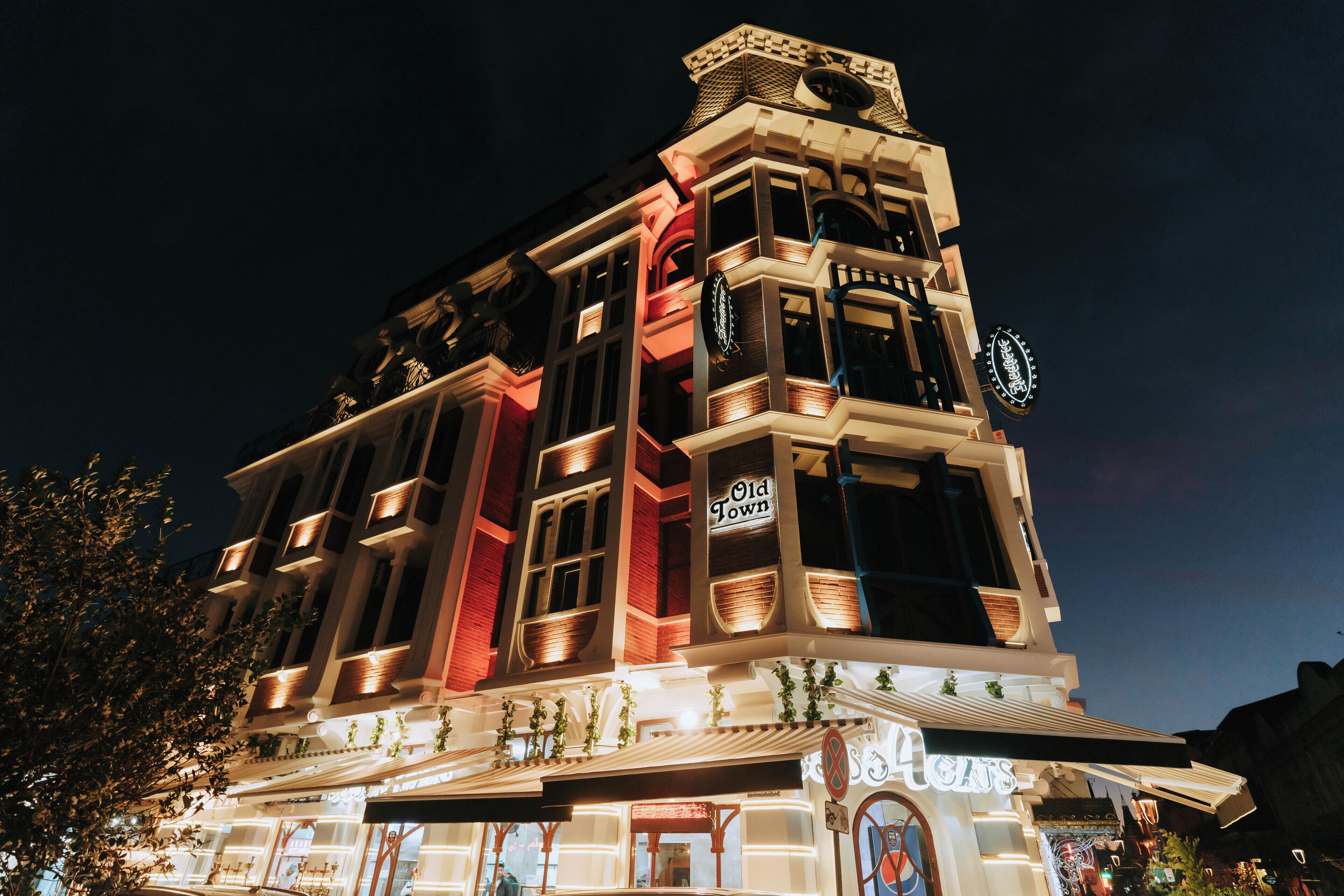 A multi-story building with a prominent 'Old Town' sign, large windows, and a balcony with plants.
