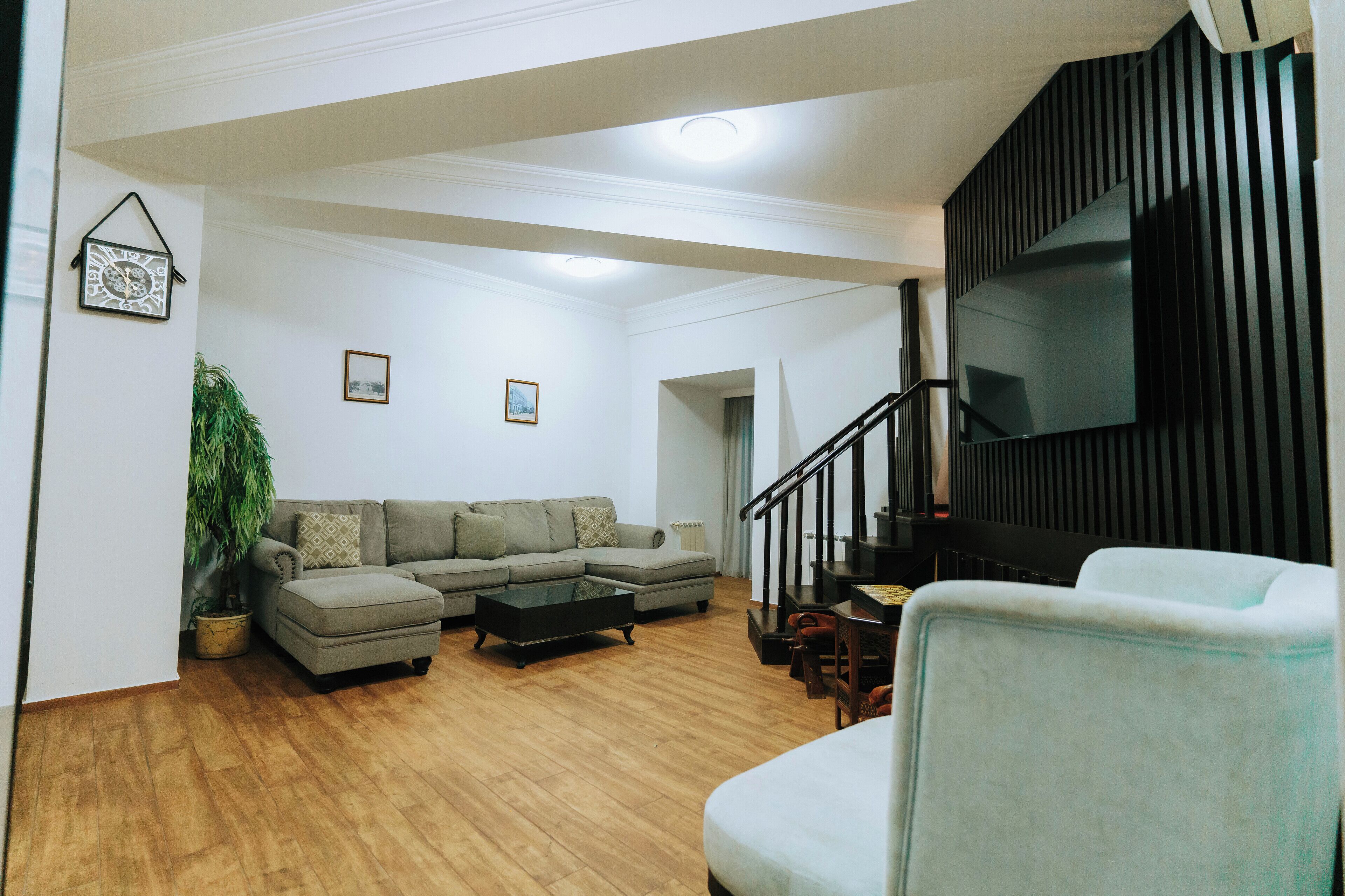 A spacious living room with a sectional sofa, a coffee table, and a staircase leading to an upper level.