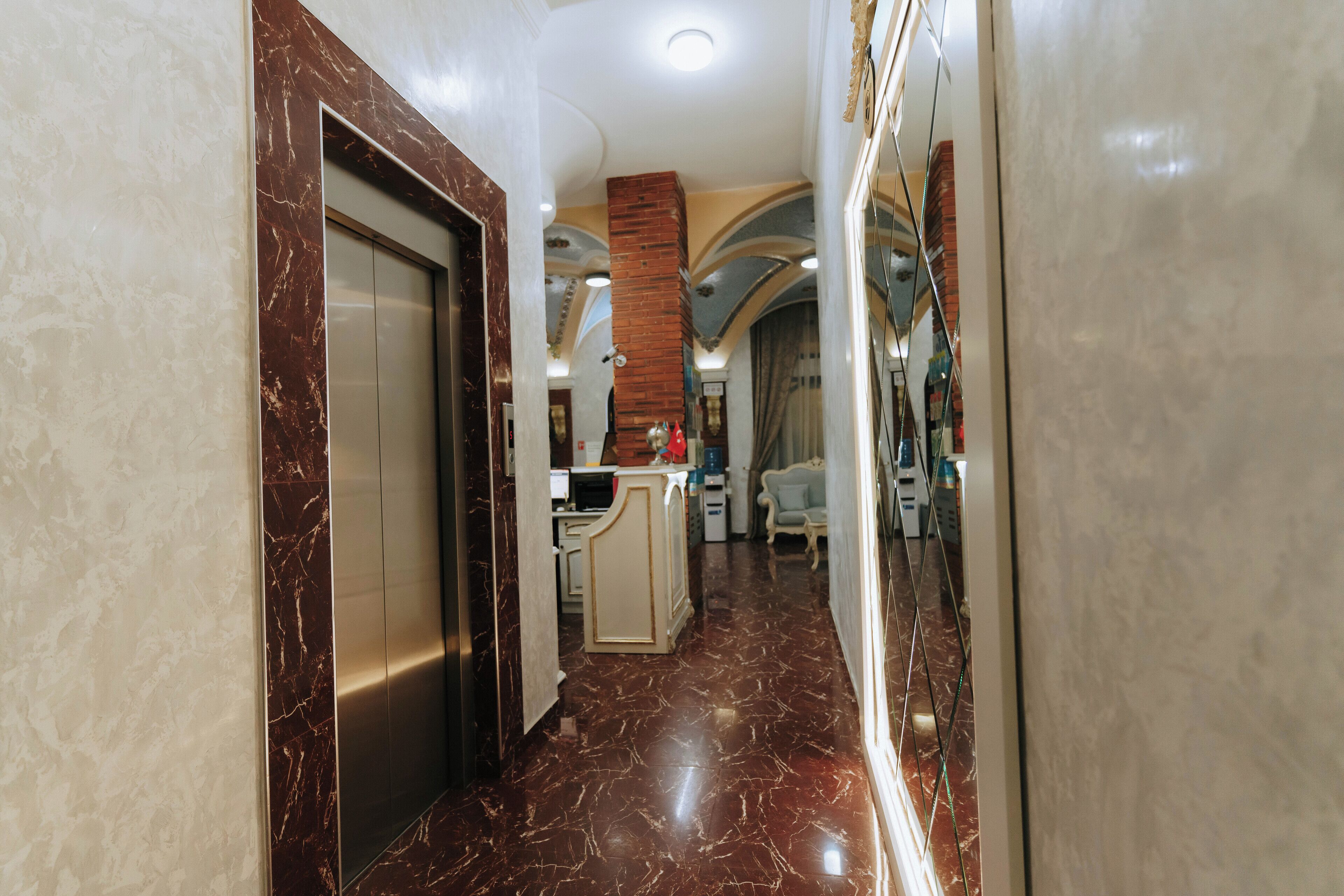A hallway with a marble floor, a door, and a staircase leading to an upper level.