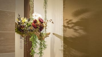 Un arreglo floral sobre una mesa en una habitación con pared de azulejos y una ventana.