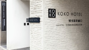Entrada de un hotel con un cartel que dice "KOKO HOTEL" y "HAKATA SHINKANSENGUCHI".