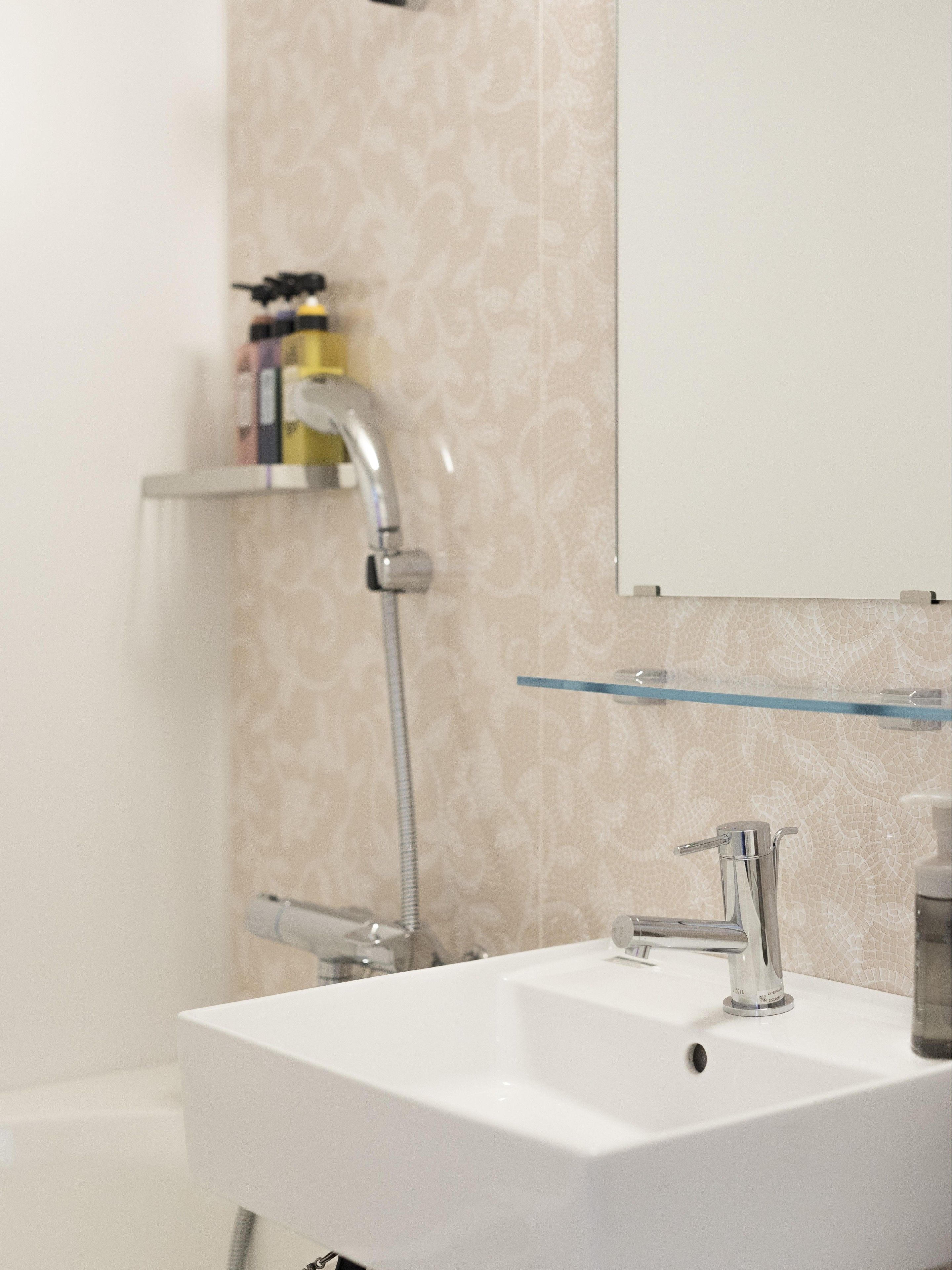 Ein Badezimmer mit einem weißen Waschbecken, einem Spiegel und einer Dusche.