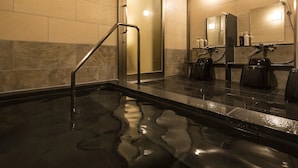 Un baño moderno con ducha de vidrio, un lavabo negro y un espejo sobre el lavabo.