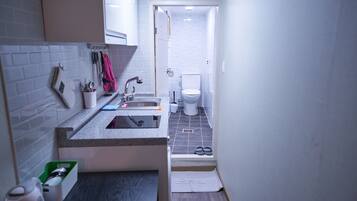 A compact bathroom with a sink, toilet, and shower.