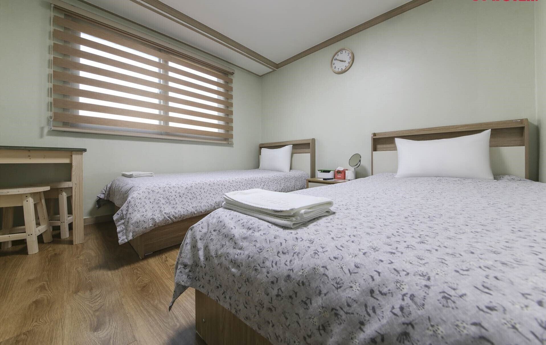 Un dormitorio con dos camas, un escritorio y una ventana con persianas.