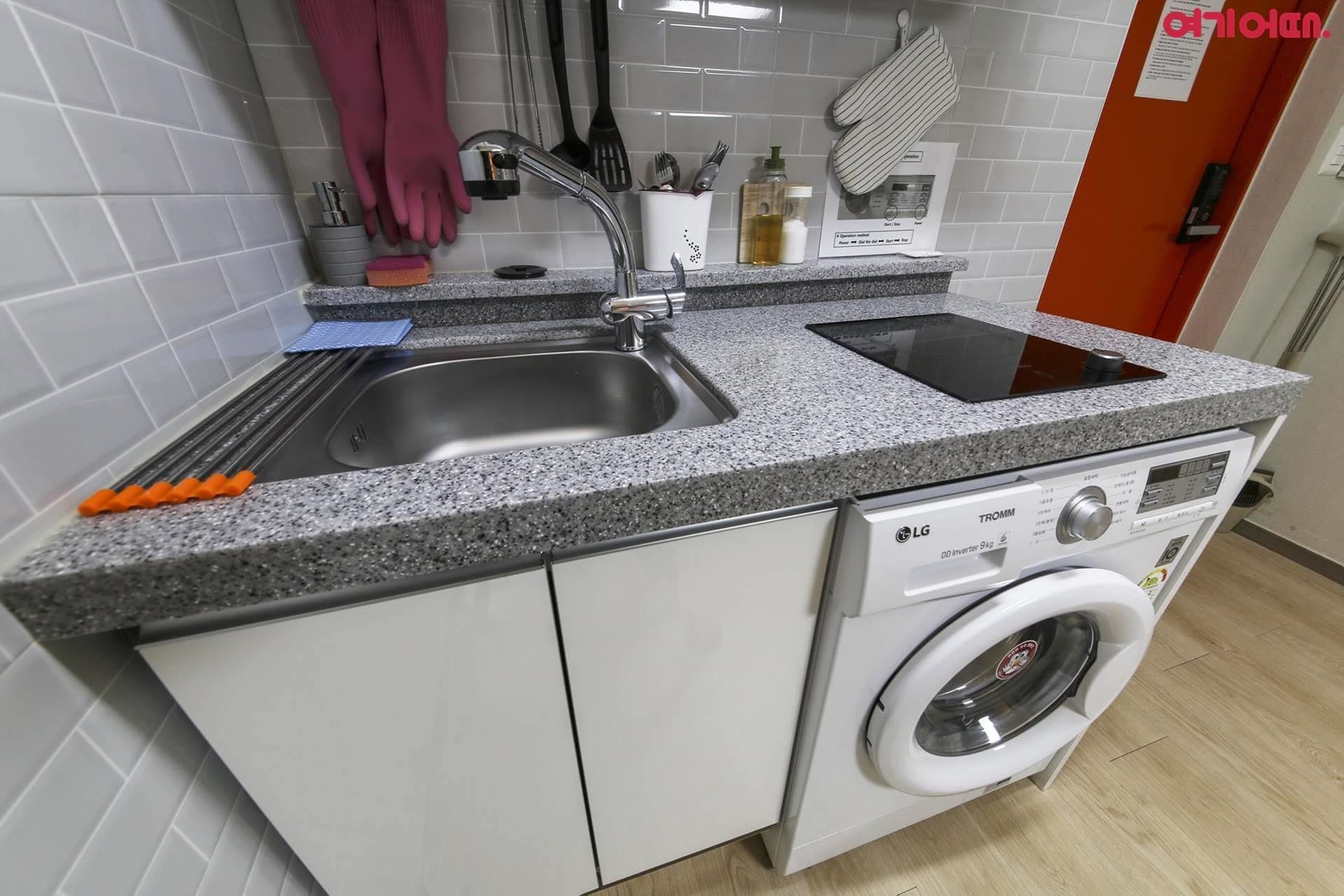 A compact kitchen with a sink, double oven, and washing machine.