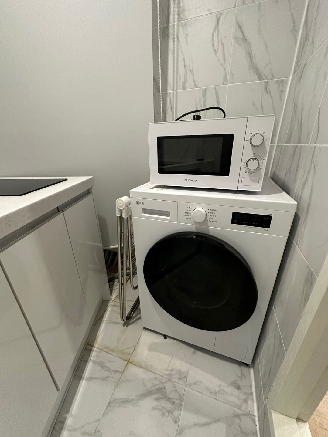 A compact laundry area with a washing machine and a microwave on top.