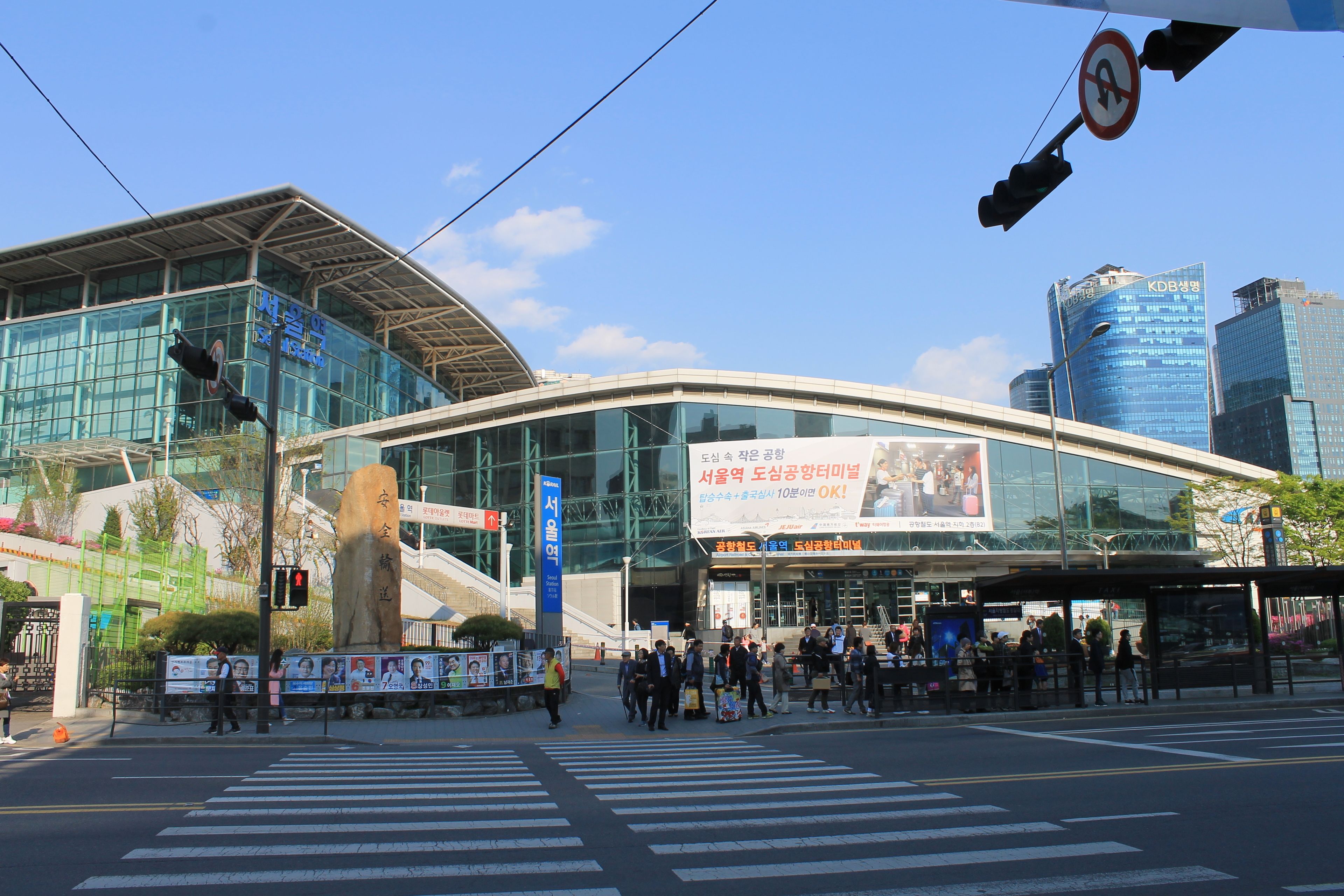 A modern building with a glass facade, a large billboard, and a pedestrian crossing.