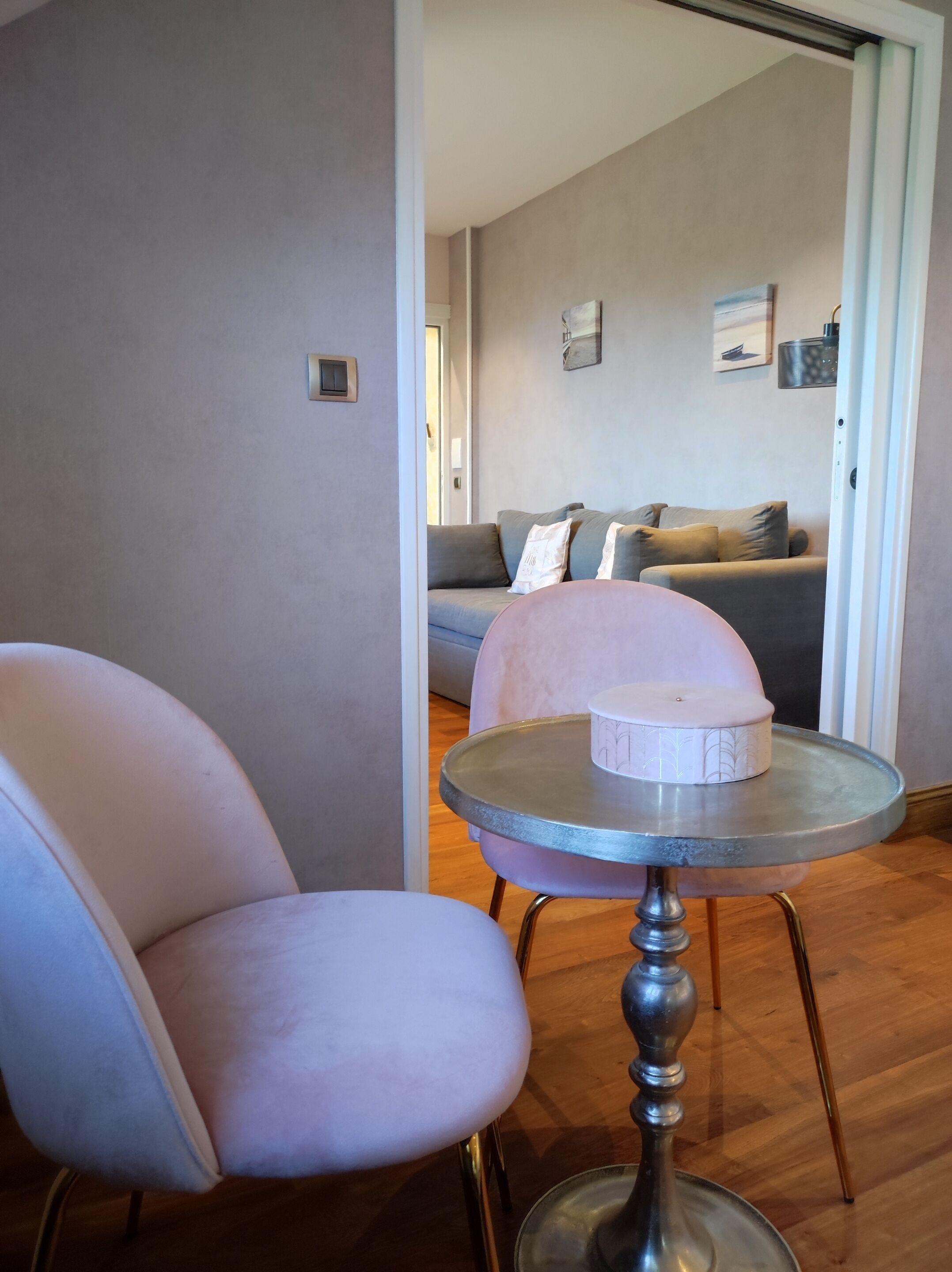Ein modernes Wohnzimmer mit einem runden Tisch, zwei Stühlen, einem Sofa und einer Tür zu einem weiteren Raum.