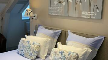 Ein Schlafzimmer mit einem großen Bett, Kissen mit Blumenmuster, einer Wandlampe und einem Blumenbild.