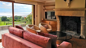 Una sala de estar con chimenea, televisión y vistas al océano.