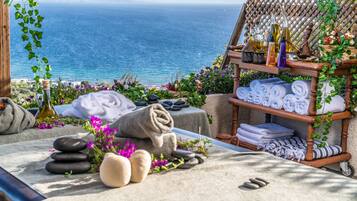 Relax in a serene spa setting with ocean views, featuring a bench, towels, and soothing spa amenities.