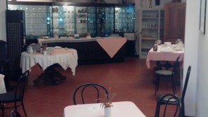 A dining area with tables and chairs, a glass display cabinet, and a wooden cabinet. - Albergo Niki (Zelo Buon Persico)
