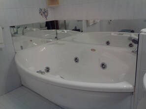 A large, freestanding bathtub in a bathroom with a mirror above it.
