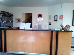 A reception desk with a clock, framed pictures, and a small statue on the wall.
