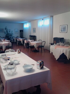 A dining area with tables set for a meal, including plates, bowls, and a HAG coffee machine.