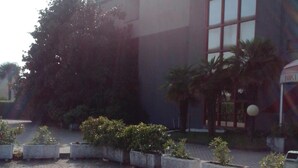 A building with a modern architectural style, featuring a large glass facade and a series of rectangular planters with greenery. - Albergo Niki (Zelo Buon Persico)