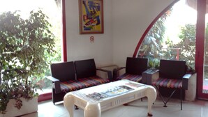 A room with a sofa set, a coffee table, and a large potted plant. - Albergo Niki (Zelo Buon Persico)