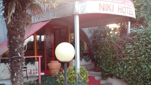 A hotel entrance with a red awning, a lamp post, and a staircase leading to the entrance. - Albergo Niki (Zelo Buon Persico)