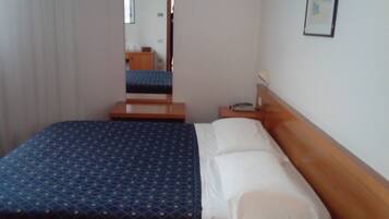A hotel room with a bed, a nightstand, a mirror, and a framed picture on the wall.