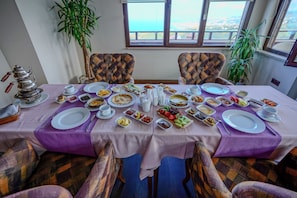 A dining table set with various dishes and a teapot, surrounded by chairs with checkered upholstery. - Sera Lake Resort Hotel Spa & Aparts (Akçaabat)
