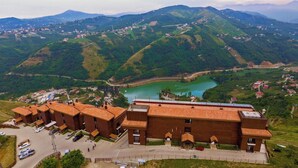 Um hotel com um pátio, rodeado por colinas verdes exuberantes e um lago.