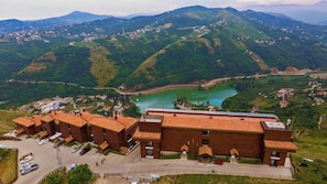 A hotel with a courtyard, surrounded by lush green hills and a lake. - Sera Lake Resort Hotel Spa & Aparts (Akçaabat)