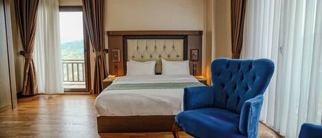 Une chambre d’hôtel avec un lit, un fauteuil bleu, un plancher en bois et une vue par la fenêtre.