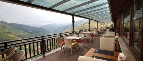 Una terraza con mesas y sillas con vistas a un paisaje montañoso.