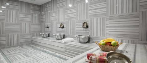 Une salle de bain moderne avec des murs recouverts de carreaux à rayures, un plan de toilette en marbre et un panier de fruits.