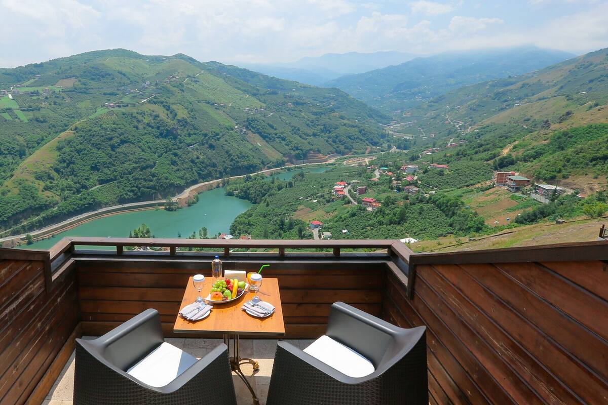 A table with a view of a valley and a lake.