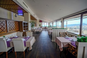 A restaurant with tables set for dining, a ceiling with a wooden pattern, and large windows offering a view. - Sera Lake Resort Hotel Spa & Aparts (Akçaabat)
