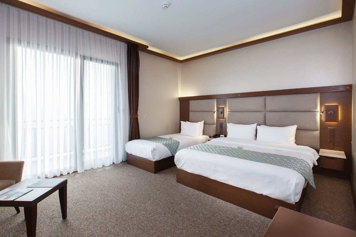 A hotel room with two beds, a desk, and a chair.