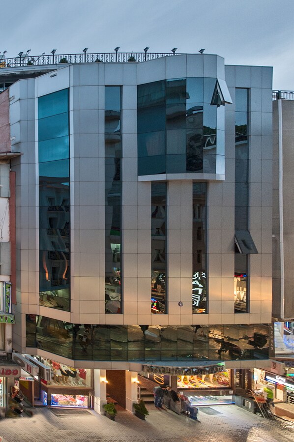 Un edificio moderno con fachada de vidrio, varios pisos y locales comerciales en la planta baja.