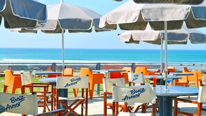 Espace extérieur aménagé avec des tables et des chaises, des parasols et une vue sur l’océan.