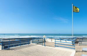 Une promenade en bord de mer agrémentée d’un mât avec un drapeau, de garde-corps et offrant une vue dégagée sur l’océan.