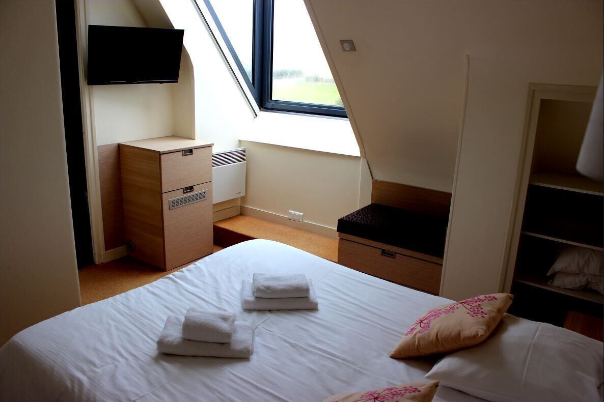 Une chambre à coucher comprenant un lit, un téléviseur fixé au mur, un bureau et une armoire.