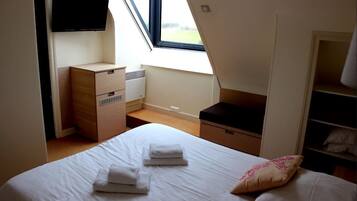 Une chambre à coucher comprenant un lit, un téléviseur fixé au mur, un bureau et une armoire.