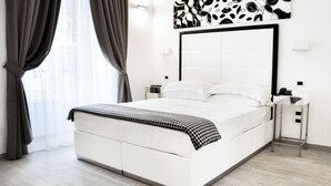 Une chambre d’hôtel moderne avec un grand lit, une table de chevet, une petite table et une œuvre d’art accrochée au mur.