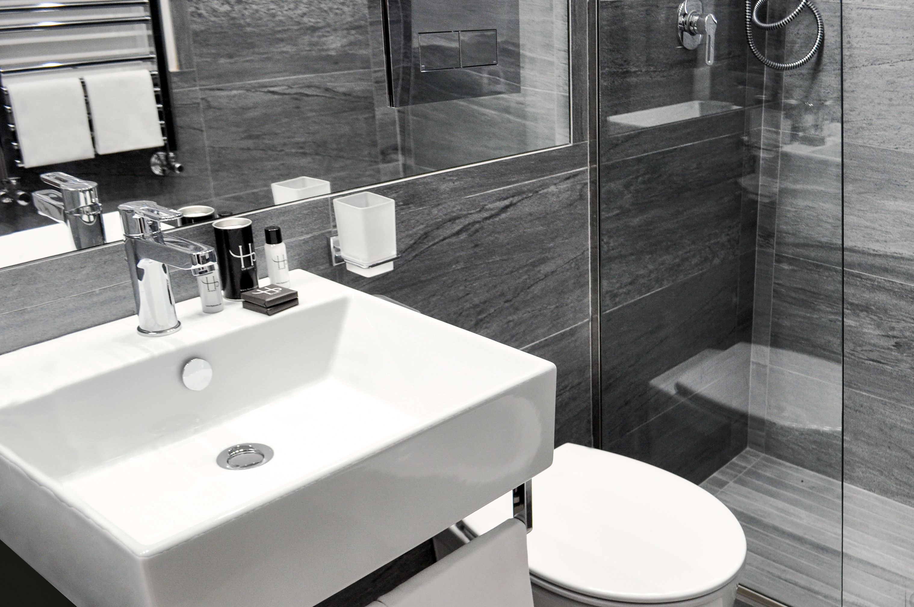 A modern bathroom with a white sink, a mirror, a toilet, and a glass shower enclosure.