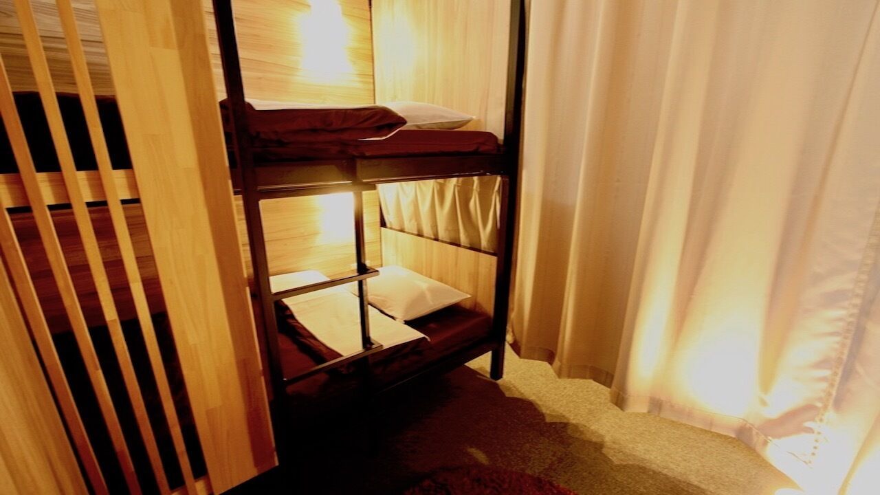 Ein Stockbett mit Holzrahmen, einer Matratze und einem Kopfkissen.