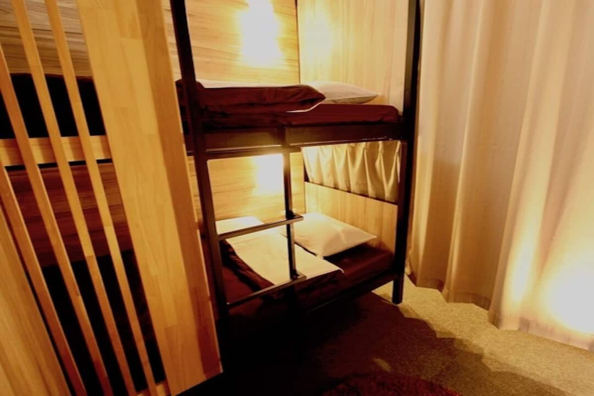Ein Stockbett mit Holzrahmen, einer Matratze und einem Kopfkissen.