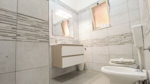 Un baño moderno con un tocador blanco, un lavabo y un inodoro.