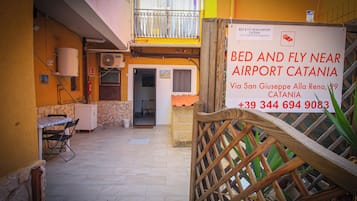 Un estrecho callejón que lleva a una propiedad con un cartel que indica que es un bed and fly cerca del aeropuerto de Catania.
