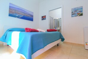 A bedroom with a bed, a large window, and a painting of a coastal scene. - Bed & Fly near Airport Catania (Catania)