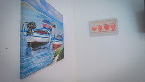Una pared con un cuadro de barcos y una pequeña foto enmarcada con corazones.